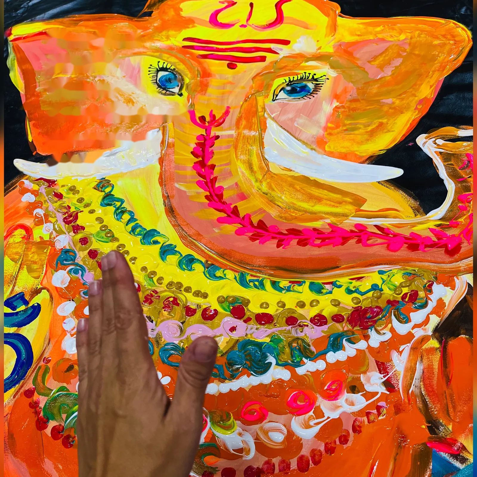 Ganesha by Yana Yank: the elephant-headed deity in blazing orange and yellow, adorned with rows of pink, red and turquoise jewel-like dots; the artist's hand rests on the canvas