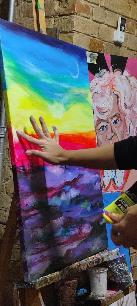 Yana Yank painting a rainbow-coloured canvas by hand in her studio