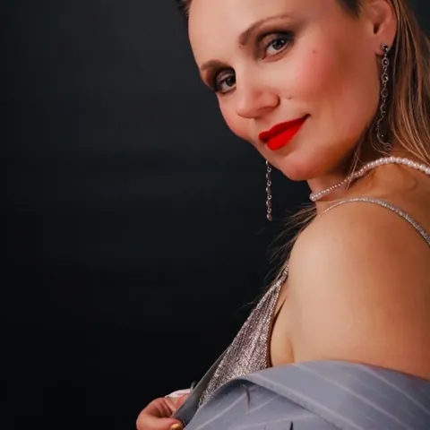 Portrait of the artist Yana Yank in a silver dress against a dark background